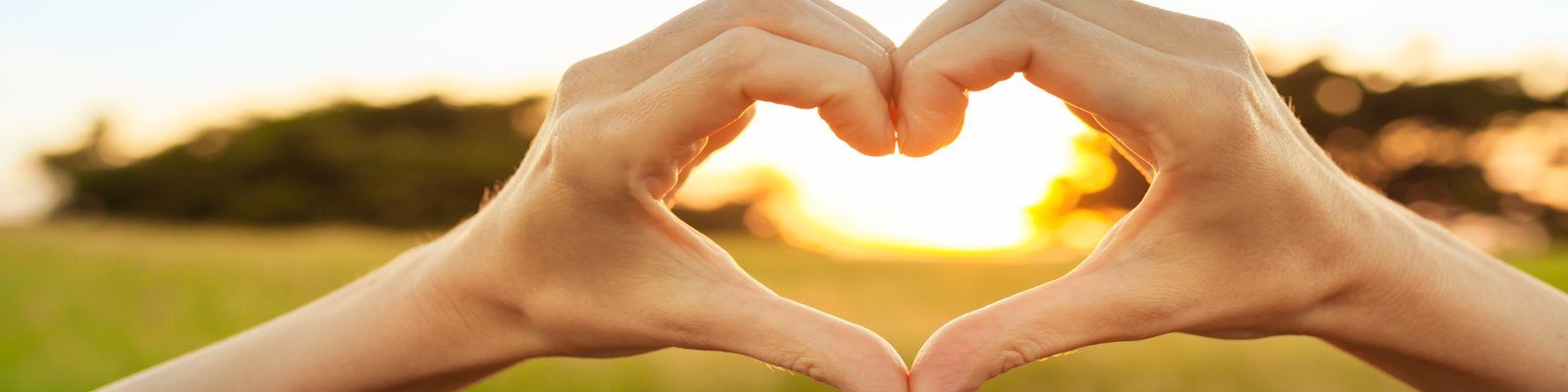 hands making a heart shape to frame the sun