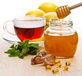 Tea with lemon, garlic, capsules and honey on white background