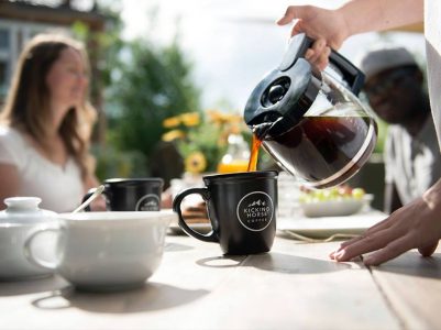 Person pours organic, non-GMO coffee from Kicking Horse into a cup outside.