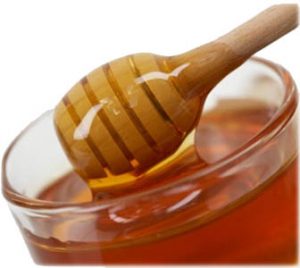 Clear bowl of honey with honey dipper.
