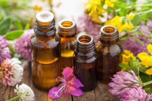 bottles of essential oils surrounded by flowers and herbs