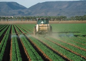 A tractor spreads pesticides