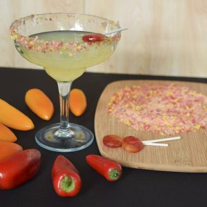Cocktail with Yum Earth Hot Chili Mango pops. Glass is surrounded by chili peppers 
