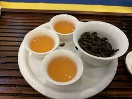 teacups filled with oolong tea, plus a bowl of oolong tea leaves