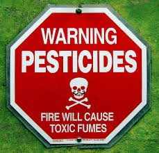 A stop-sign-like sign reads "Warning. Pesticides. Fire will cause toxic fumes."