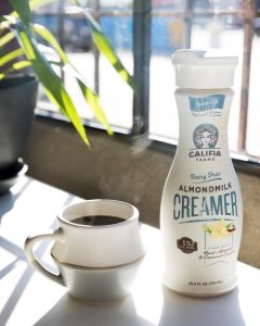 Califia Farms almond milk creamer sitting next to cup of coffee