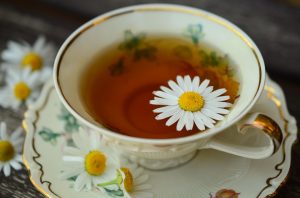chamomille tea in cup with chamomile blossoms