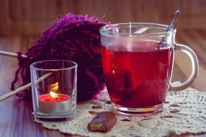 Red fruit tea with knitting project, candle, and chocolate