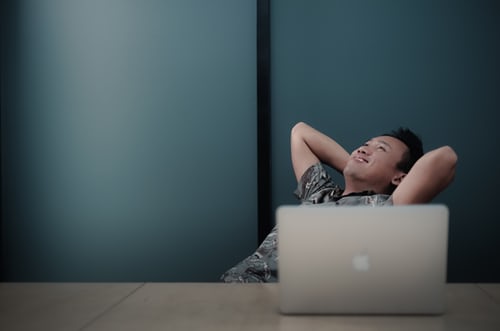 man kicking back in front of laptop.