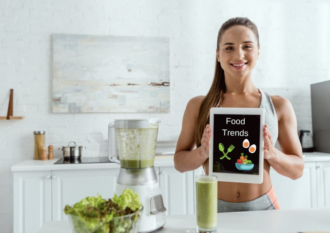 what consumer drivers influence food trends? a woman making a green smoothie holds an iPad that reads food trends