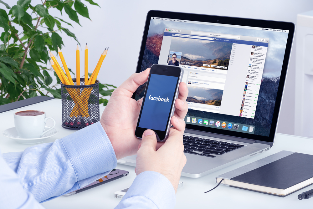 why use Facebook ads for dropshipping? Image of man using Facebook on mobile and laptop