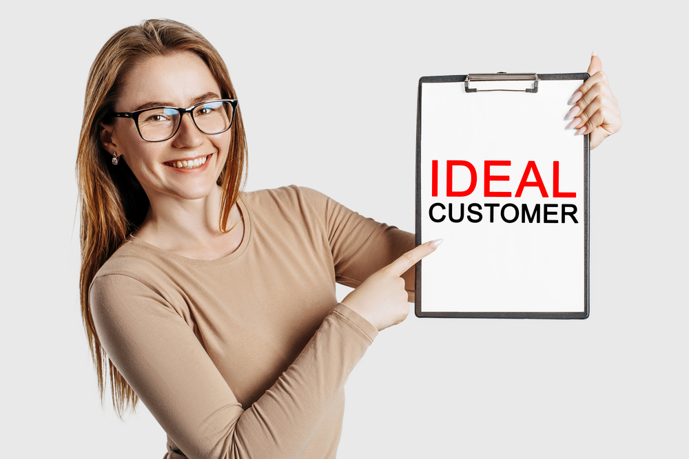 Finding your target audience. Woman holds clipboard with ideal customer written on it.
