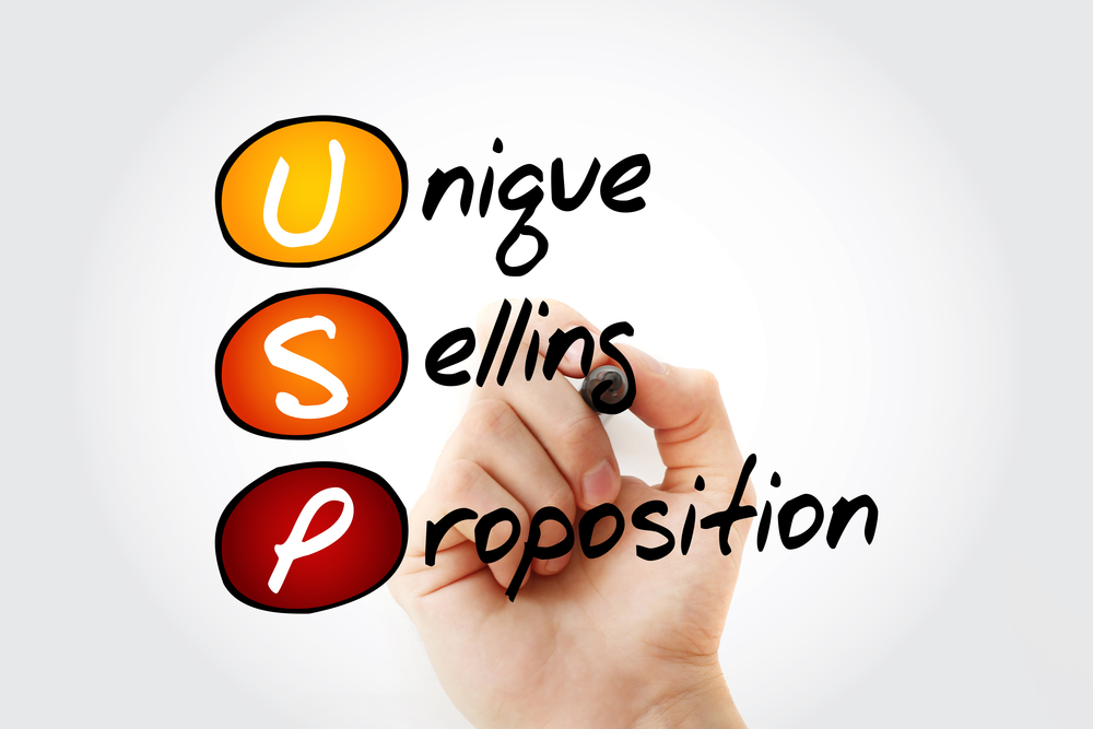 Hand writing the words "unique selling proposition" on a board. Developing a marketing plan for dropshipping.