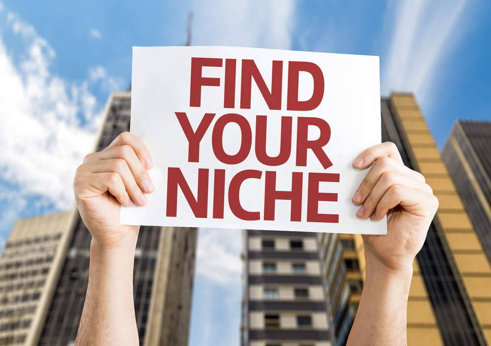Hands holding up a sing that reads 'find your niche'. First step in building an online store.