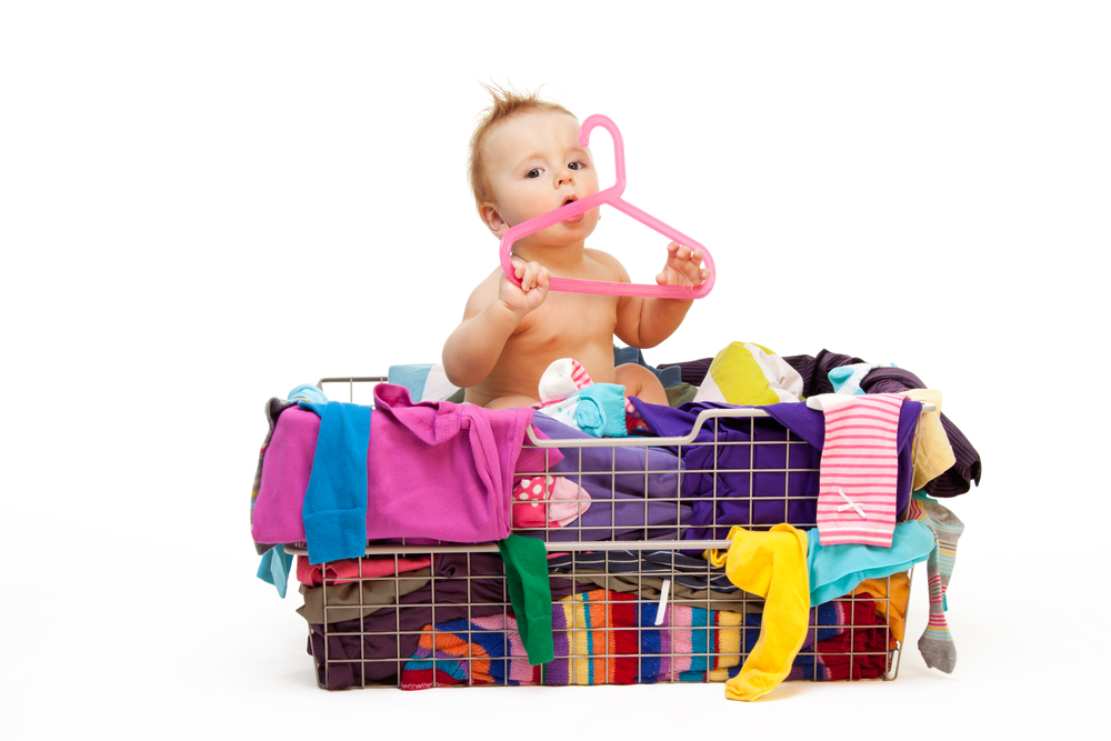 a baby in a basket full of various baby products.