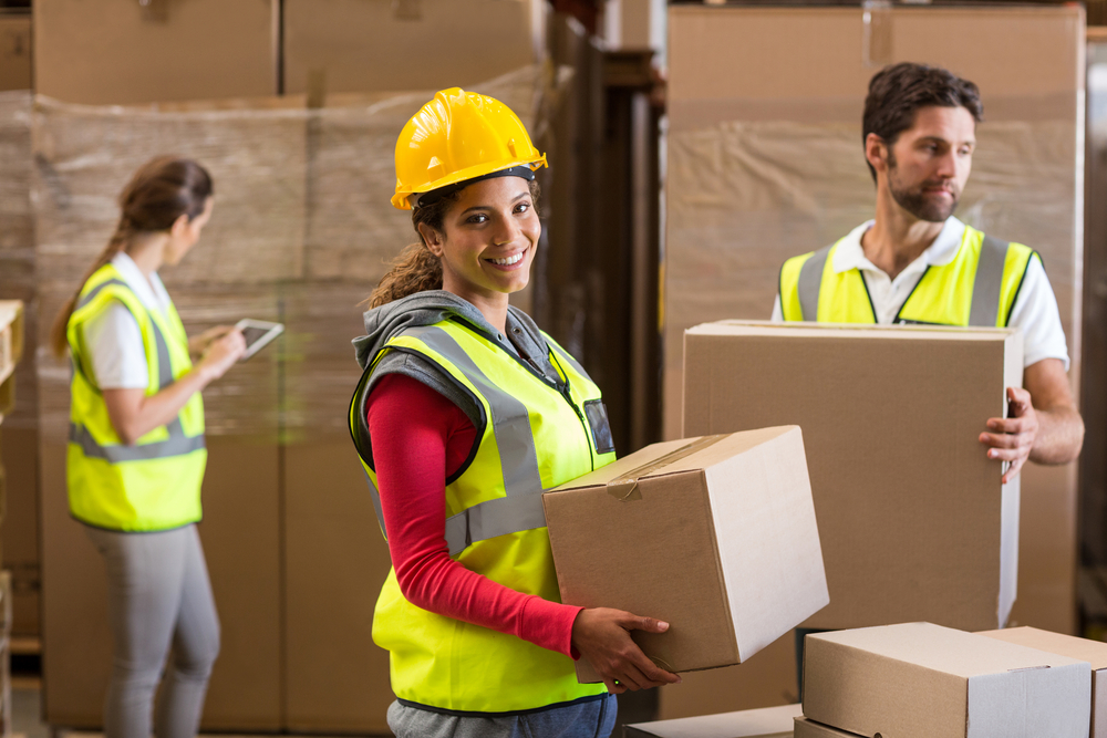 woman working in a dropshipping warehouse carrying a package. 