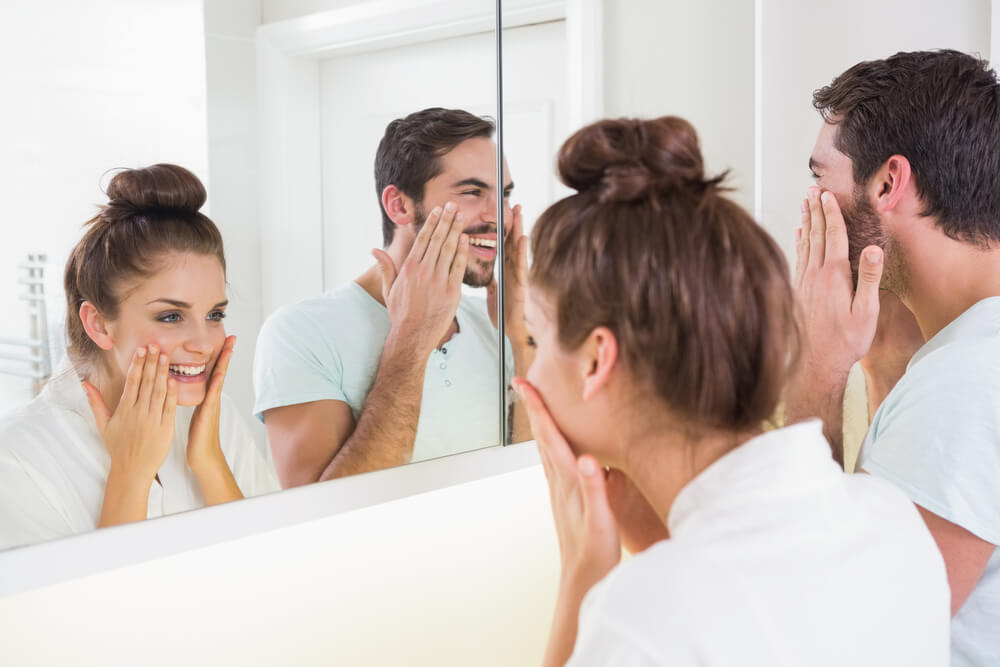 man and woman at the mirror in the bathroom applying skin care products