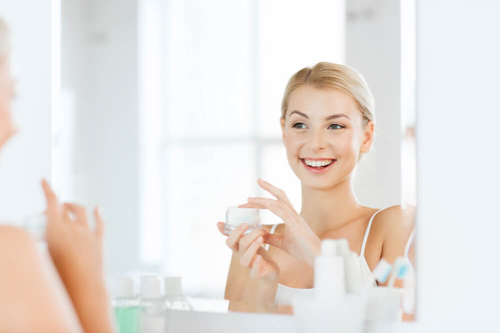 woman at vanity applying wholesale skin care products to her face