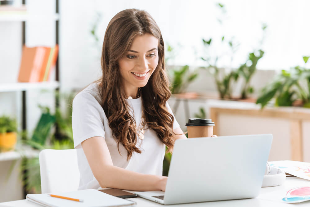 market your ecommerce store. a woman smiling on her laptop working.