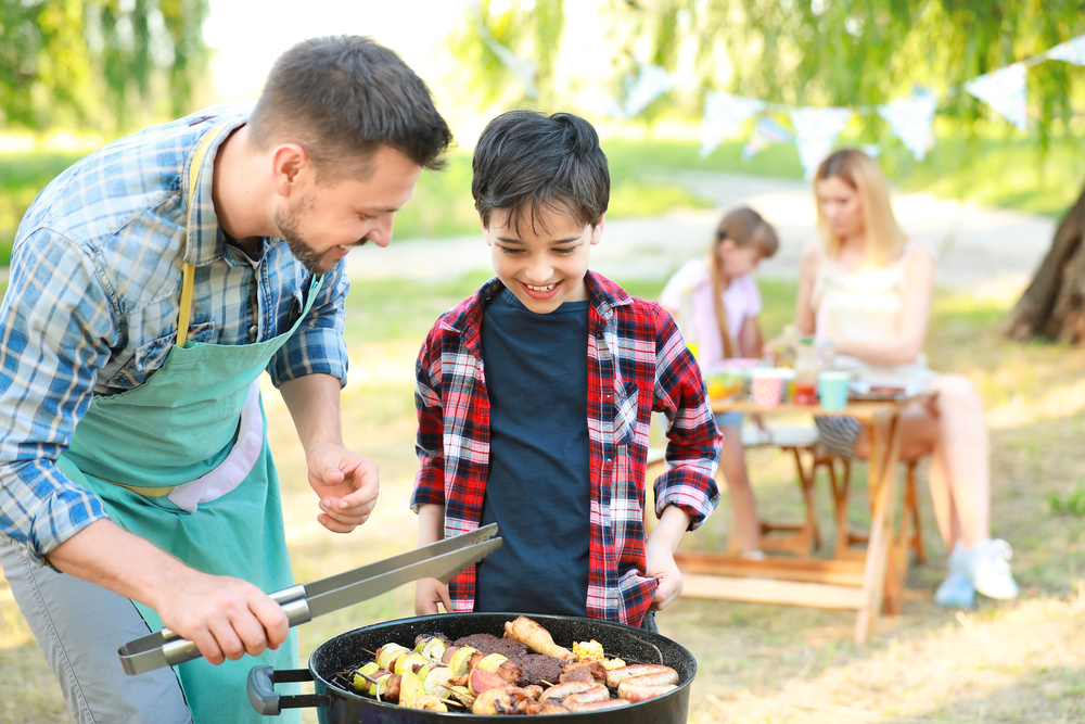 summer dropshipping trends - a boy and his father barbecuing outdoors in a park