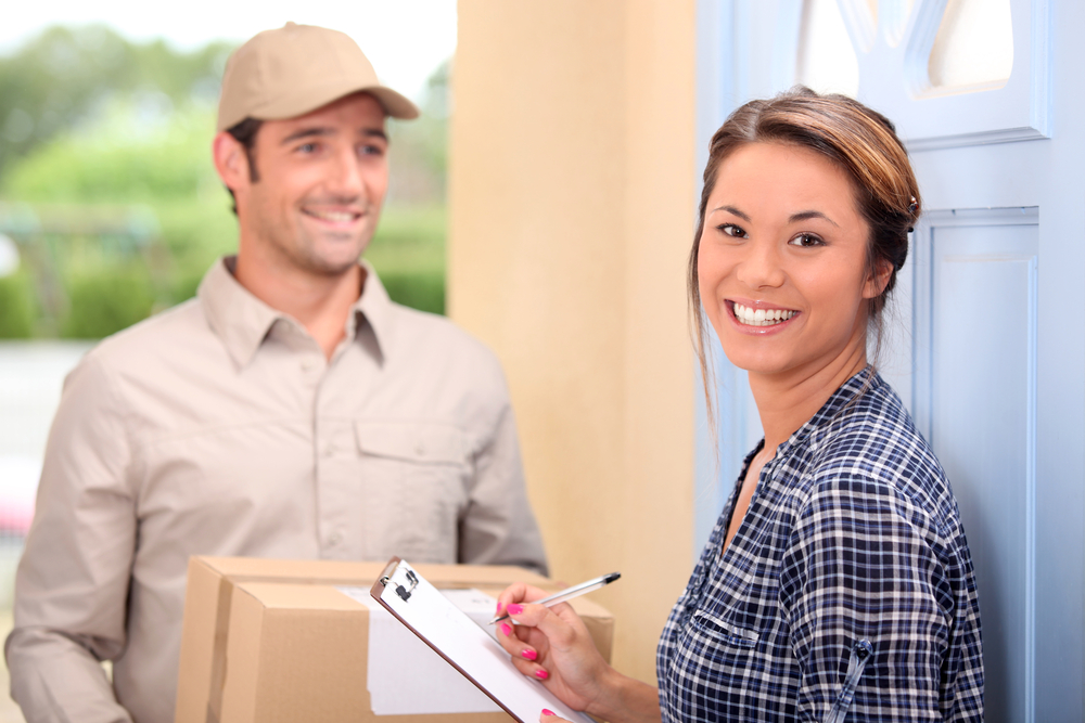 a delivery man bringing a package to a woman at home