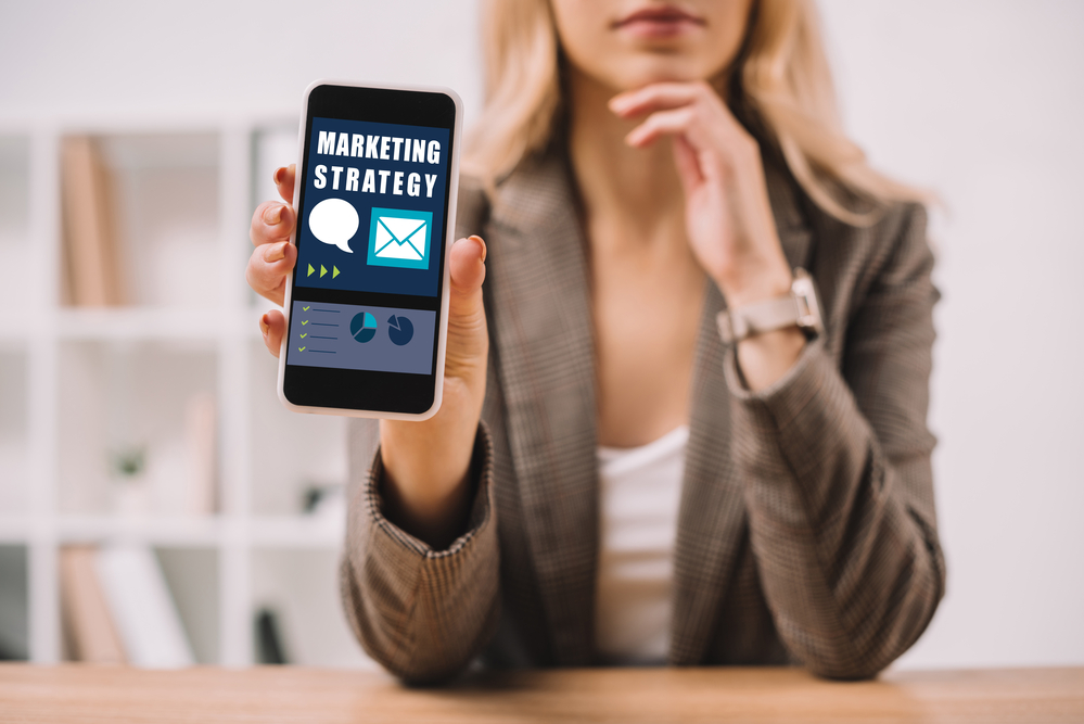 woman holding a smartphone displaying a marketing strategy