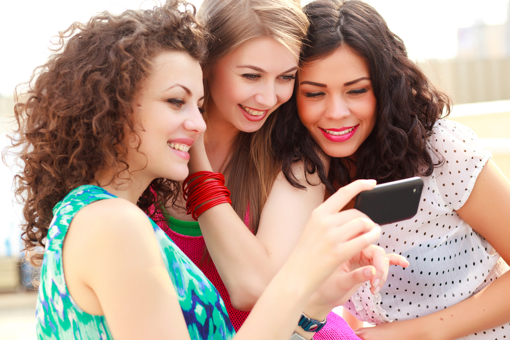three women watching videos on social media on a smartphone