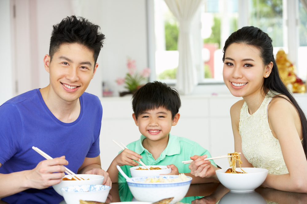 Asian family eating dinner together at the table.